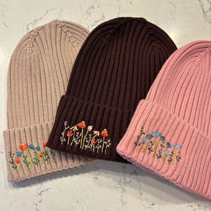 3 beanies with dainty embroidered floral design in bottom left corner.