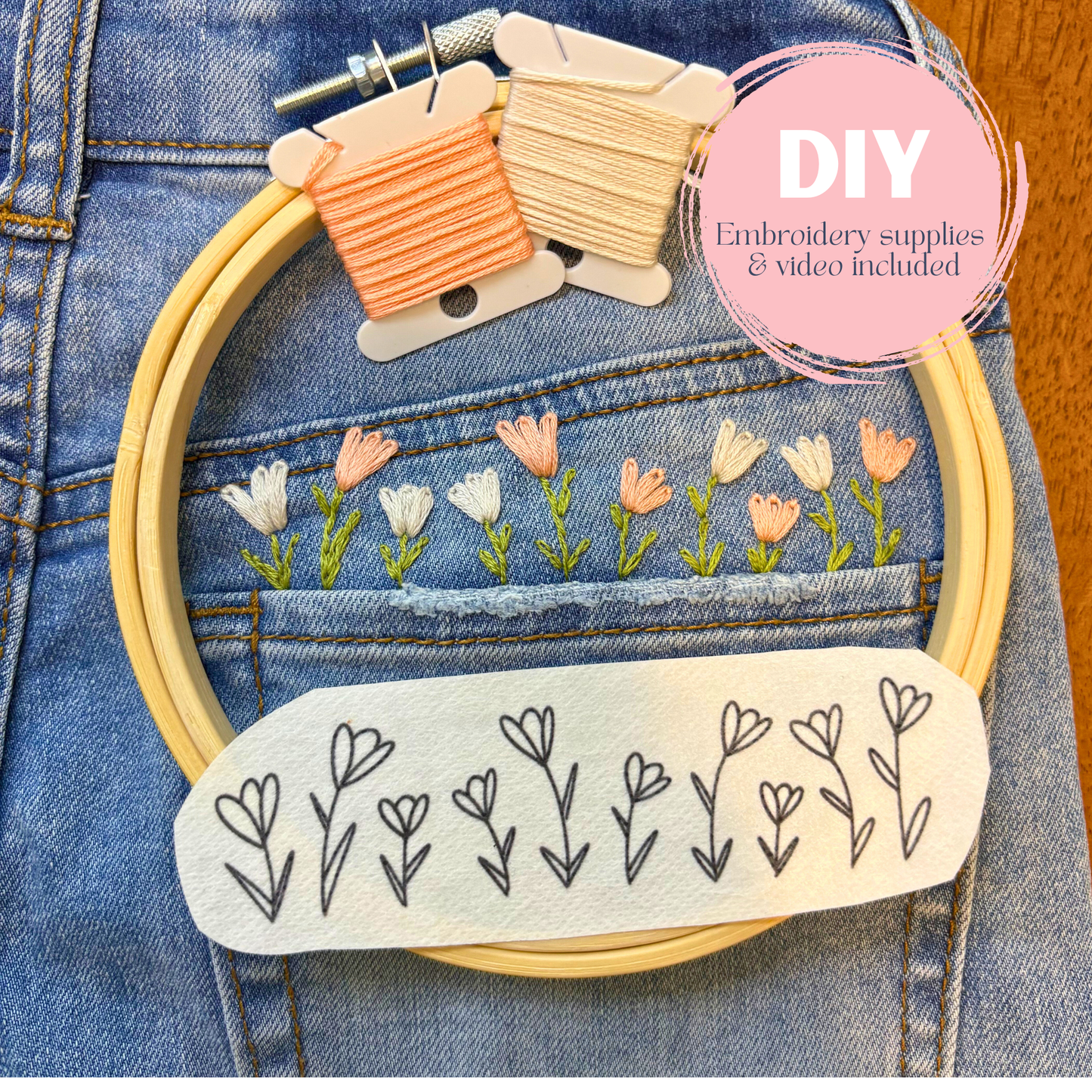 Embroidery hoop with floral design on denim fabric, including embroidery thread and pattern guide.