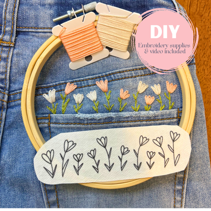 Embroidery hoop with floral design on denim fabric, including embroidery thread and pattern guide.