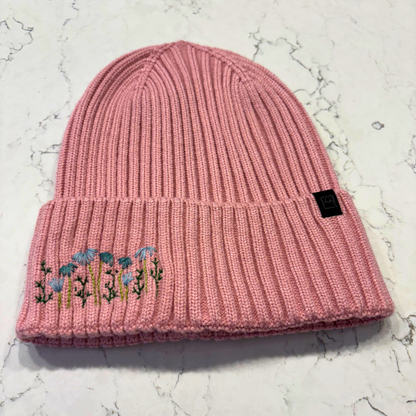 Light pink beanie with dainty embroidered floral design in bottom left corner.