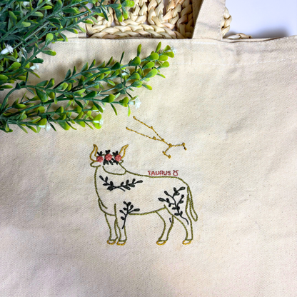 Tote bag with embroidered Taurus design and decorative elements on a neutral background.