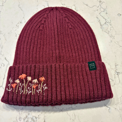 Maroon beanie with dainty embroidered floral design in bottom left corner.