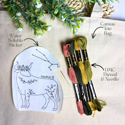 Embroidery kit with Taurus design, thread, needle, and water-soluble sticker on a beige background.