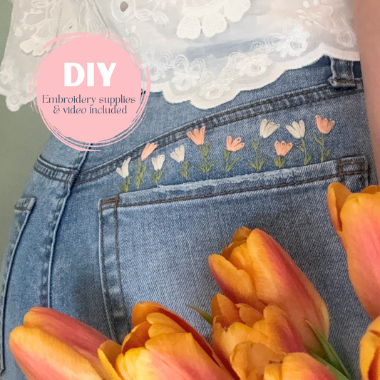 Denim jeans with floral embroidery and tulips in the foreground