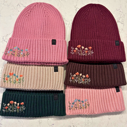 6 different colored beanies with dainty embroidered floral design in bottom left corner.